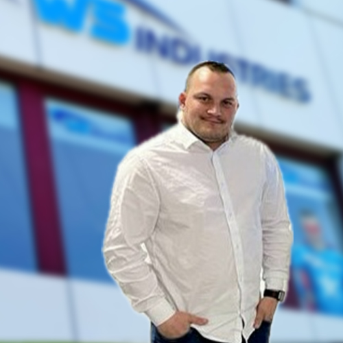 Mann vor Firmengebäude lächelt