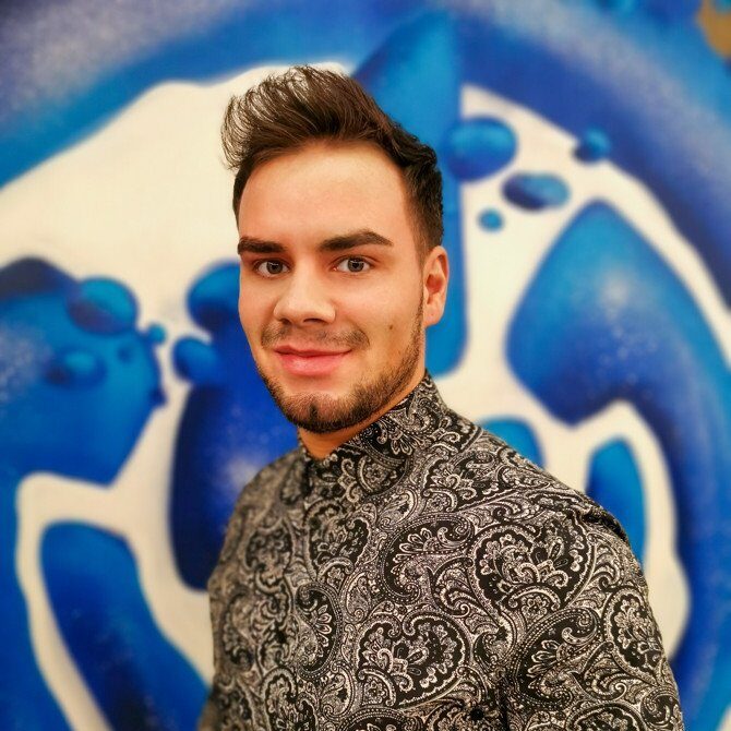 Mann in gemustertem Hemd vor blauem Wandgemälde