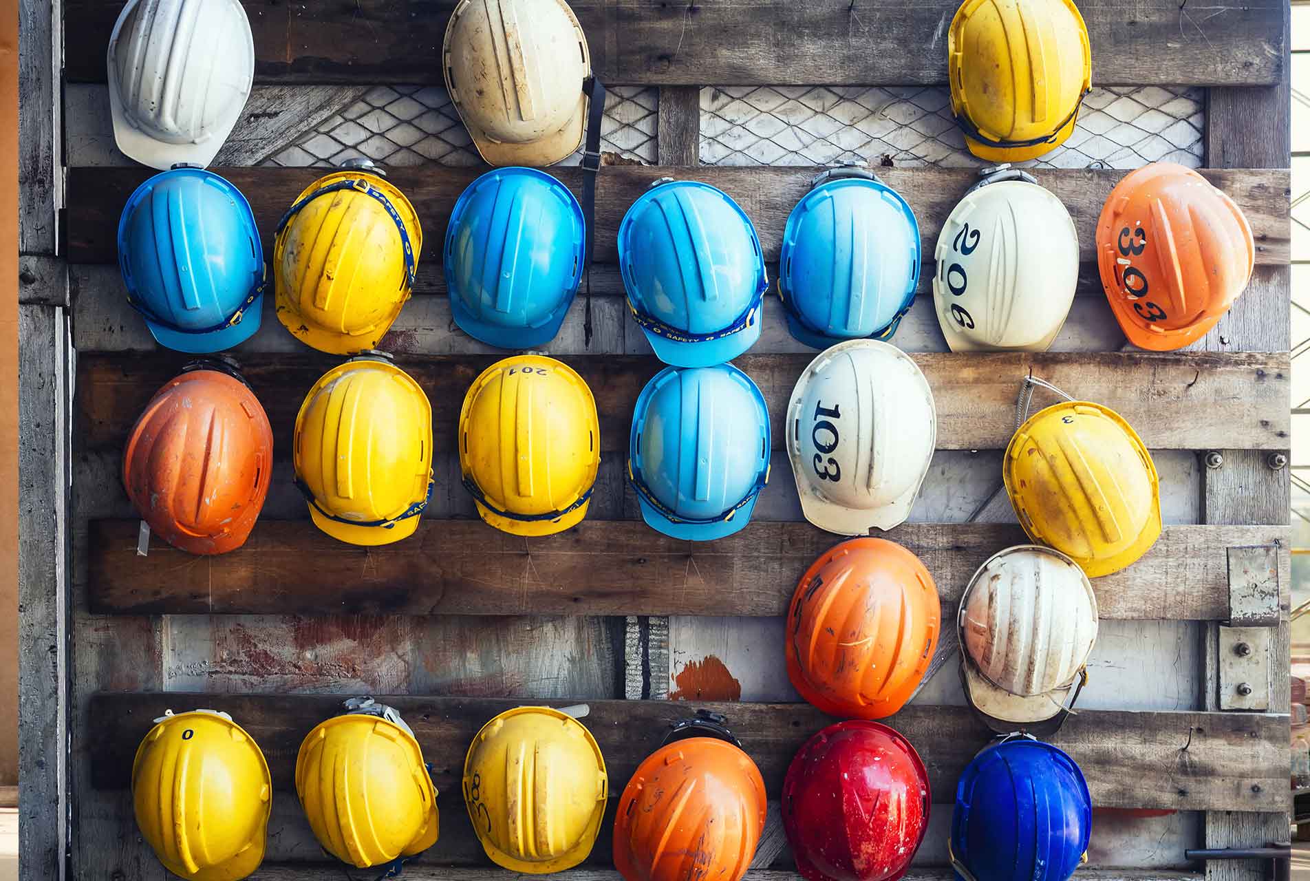 Bunte Bauhelme an einer Wand aufgehängt