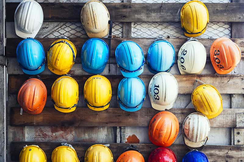Bunte Schutzhelme an Holzwand aufgehängt
