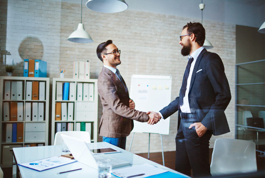 Zwei Männer geben sich im Büro die Hand