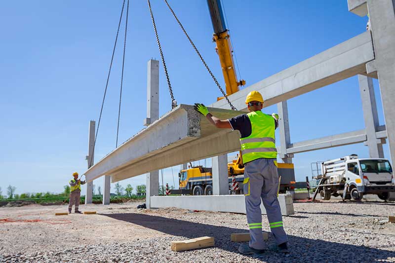 Arbeiter montieren Betonträger auf Baustelle